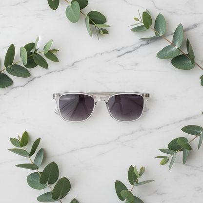 Clear sunglasses flat lay on white marble with eucalyptus leaves